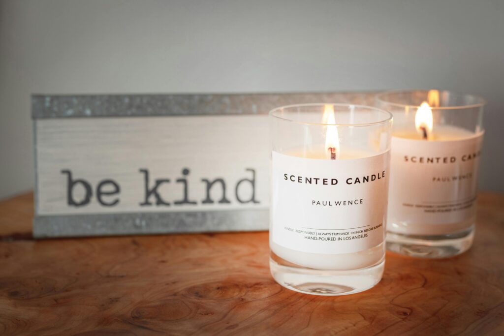 A warm setting with lit scented candles and a motivational 'be kind' sign for a cozy ambiance.